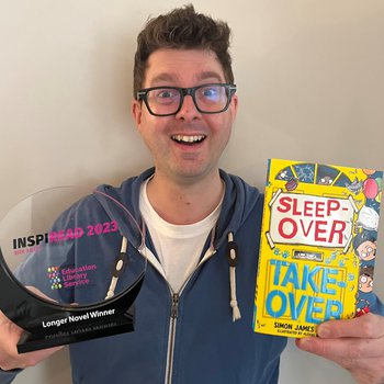 Author Simon James Green holds up a trophy and book