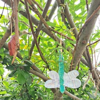 Handmade dragonfly charms hanging from branches
