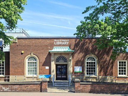 A photo of West Bridgford Library on a sunny day, surrounded by trees.