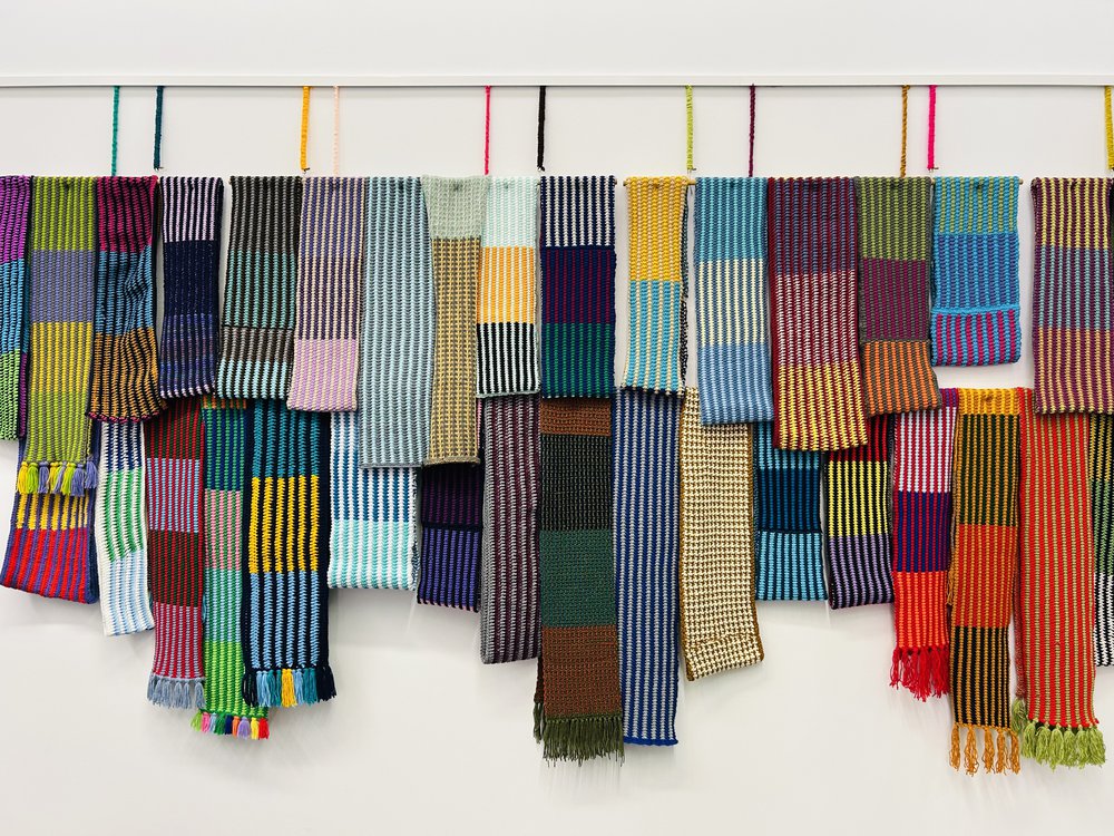 Wrapped display at West Bridgford Library Gallery, a wall of knitted hanging scarves