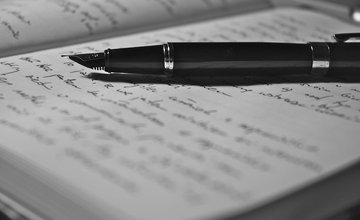 Open book with handwriting in and a fountain pen laid across the pages