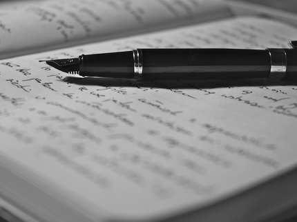 Open book with handwriting in and a fountain pen laid across the pages