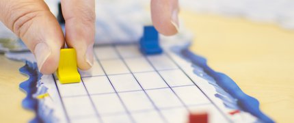 hands moving a counter on a game board