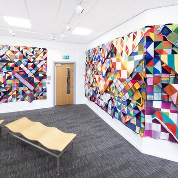 An exhibition wall of blankets with a door