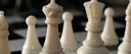 7 assorted white chess pieces on a chess board