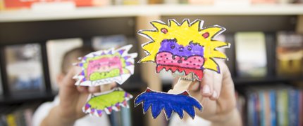children holding out homemade finger puppets