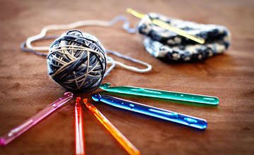 A ball of wool sat on a selection of crochet hooks