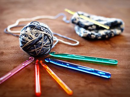 A ball of wool sat on a selection of crochet hooks