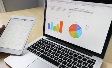 An open laptop with a graph and pie chart displayed on the screen