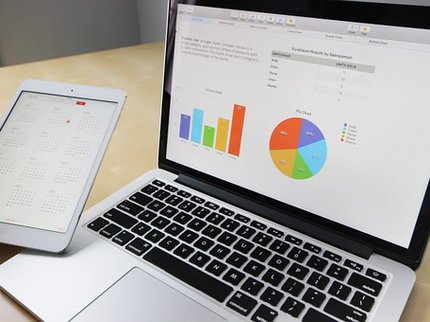 An open laptop with a graph and pie chart displayed on the screen