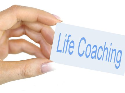 A hand holding a sign saying 'Life Coaching'