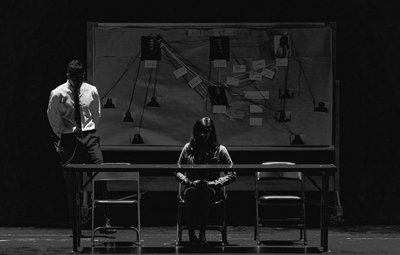 Person sat at a desk in a dark interrogation room