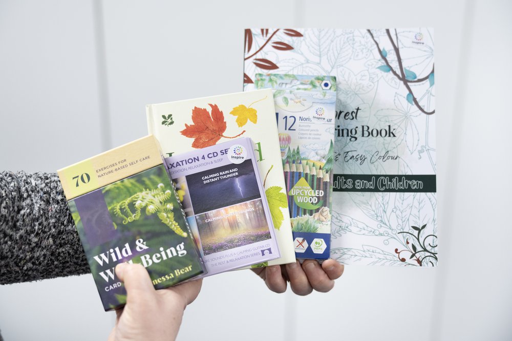 Hands hold up a collection of nature books, with a pack of colouring pencils