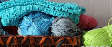 knitting wool in a wooden basket with a pair of glasses in front
