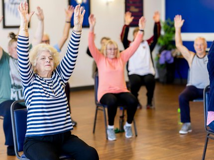 Photograph of a group of people taking part in chair based exercises