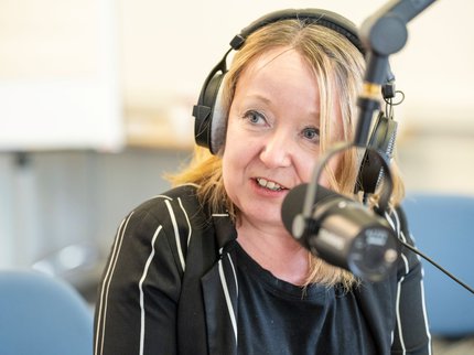 Photo of a female podcast participant with headphones and microphone.