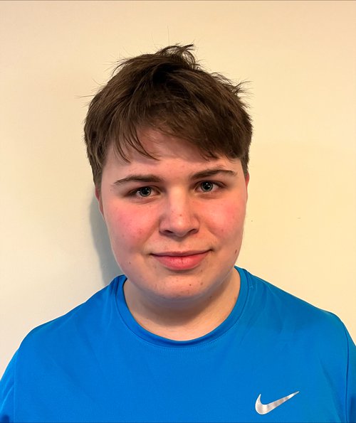 A boy wearing a blue t shirt smiling to the camera