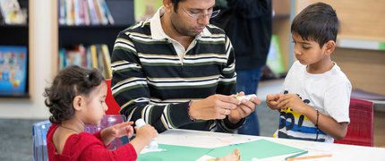 A father and children doing crafts in a library