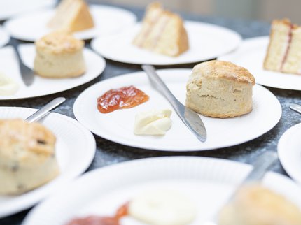 Scones with jam and clotted cream and slices of Victoria sandwich on a table
