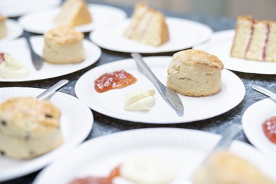 Scones with jam and clotted cream and slices of Victoria sandwich on a table