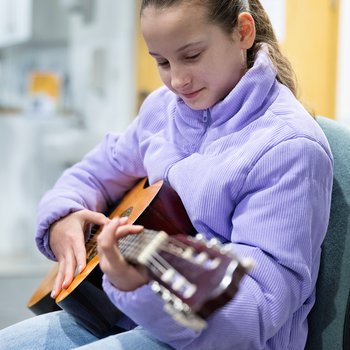 A girl playing an acoustic guitar